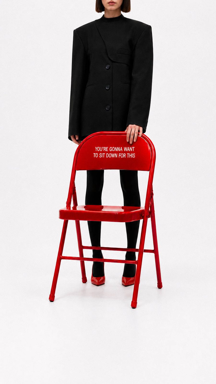 Model walking away carrying the folded red chair